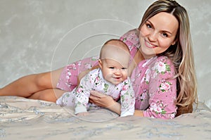 Mother and his baby daughter on the bed at home having fun