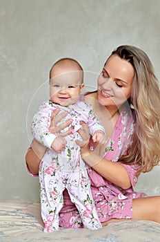 Mother and his baby daughter on the bed at home having fun