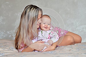 Mother and his baby daughter on the bed at home having fun