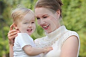 Mother hold baby on hands outdoor in summer