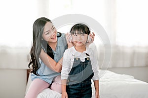 Mother hold earphone and put to her daughter to listening some music in bedroom with morning light. Concept of good relationship