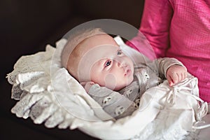 Mother hold infant baby boy on her hands, toddler covered in white blanket