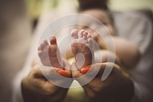 Mother holding baby feet in hands. Focus on feet.