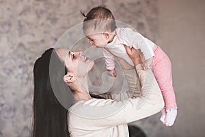 Mother holding baby girl at home. Newborn child on woman hands indoors. Motherhood. Maternity