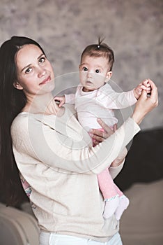 Mother holding baby girl at home. Newborn child on woman hands indoors. Motherhood. Maternity