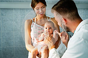 Mother holding baby for pediatrician doctor to examine