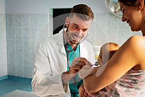 Mother holding baby for pediatrician doctor to examine