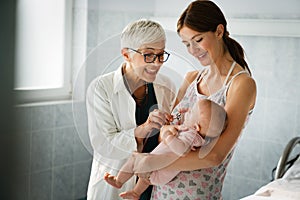 Mother holding baby for pediatrician doctor to examine