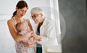 Mother holding baby for pediatrician doctor to examine