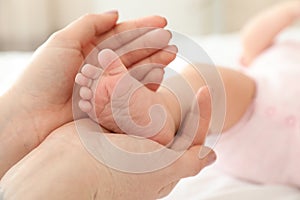 Mother holding baby`s foot on bed