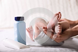 Mother holding baby`s legs on bed, closeup