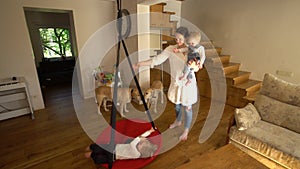 Mother holding baby son and swing boy. Two dogs indoor at home. Handheld