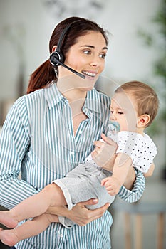 mother holding baby while talking on phone in home-office