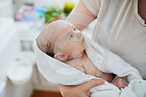 Mother holding baby wrapped in towel after bath