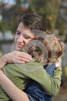 Mother holding child in her arms with love in a garden outdoors