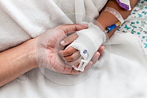 Mother holding child's hand who have IV solution