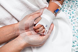 Mother holding child's hand who have IV solution