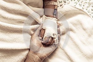 Mother holding child's hand who have IV solution in the hospital