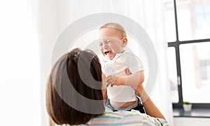 Mother holding crying little baby son at home