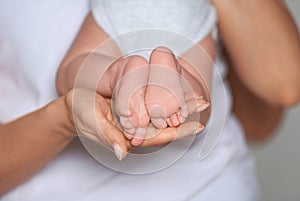 Mother holding feet of her cute little baby in hands