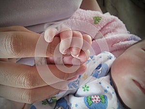 mother holding hand of her baby newborn with soft focus