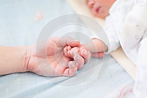 Mother holding the hand of her new born baby