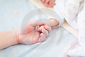 Mother holding the hand of her new born baby