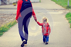 Mother holding hand of little daughter with