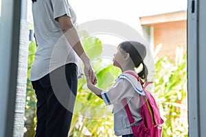 Mother holding hand of little daughter with backpack