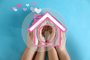 Mother holding hands with child and illustration of house on blue background. Adoption concept