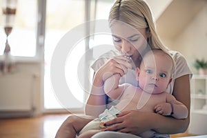 Mother holding her baby boy and kissing his hand.