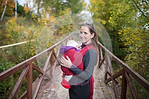 Mother holding her baby daughter, outside on wooden bridge