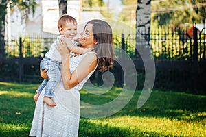 Mother holding her baby on hands in white dress