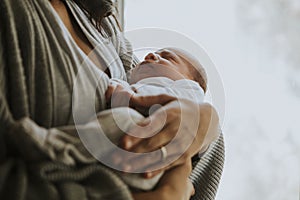 Mother holding her baby indoors