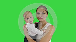 Mother holding her child and looking in to camera smiling on a Green Screen, Chroma Key.