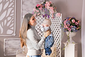 Mother holding her child. Mom playing with laughing kid. Family at home