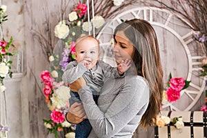 Mother holding her child. Mom playing with laughing kid. Family at home