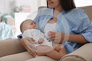 Mother holding her cute sleeping baby with pacifier at home