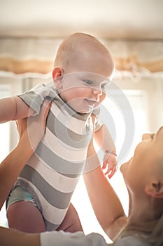 Mother holding her little baby boy in hand high.