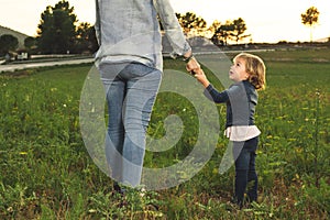 A mother holding her little daughter`s hand in the field