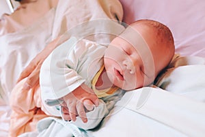 Mother holding her newborn baby child after labor in a hospital.