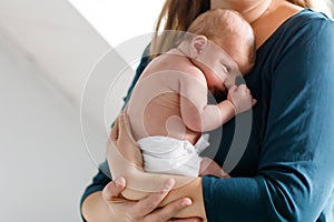 Mother holding her newborn baby daughter after birth on arms.