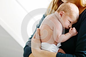 Mother holding her newborn baby daughter after birth on arms.