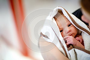 Mother holding her newborn baby daughter after birth on arms.