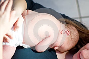 Mother holding her newborn baby daughter after birth on arms.