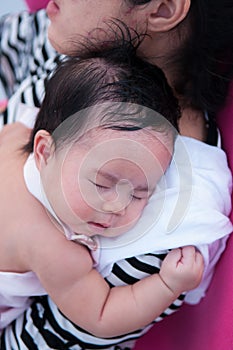 Mother holding her newborn baby in dress while her was sleeping. Mother day bonding concept with newborn baby nursing.