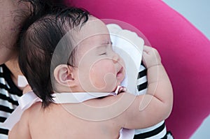 Mother holding her newborn baby in dress while her was sleeping. Mother day bonding concept with newborn baby nursing.