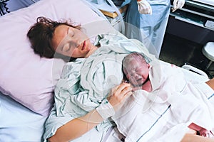 Mother holding her newborn baby after labor in a hospital.