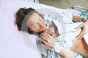 Mother holding her newborn baby after labor in a hospital.