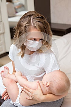 Mother holding her sick baby wearing a mask